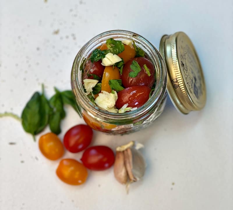 marinated cherry tomatoes with herbs and garlic in a glass jar